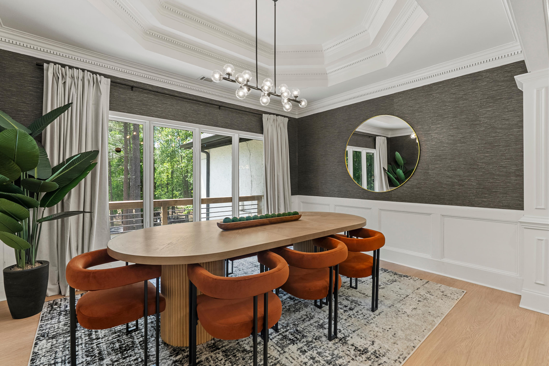 Staged dining room with round oak table and brass mirror