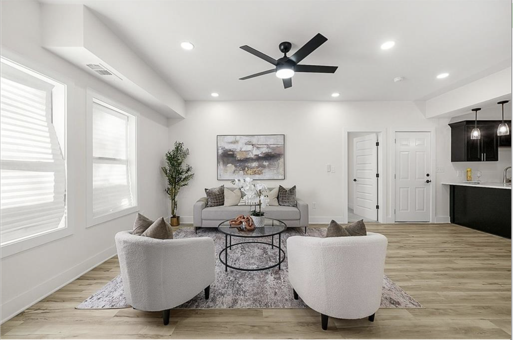 Staged open plan living room with curved accent chairs and a black kitchen